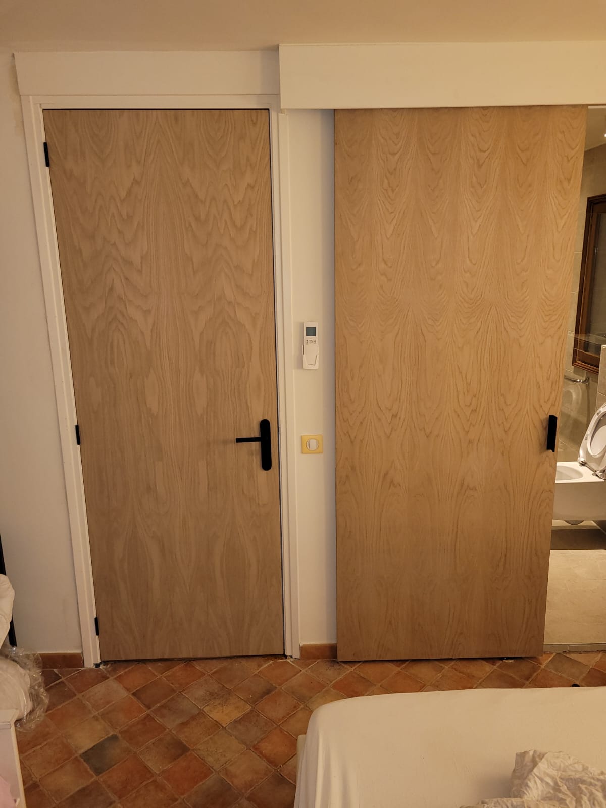 Nieuw gemonteerde eikenhouten binnendeur en houten schuifdeur met zwart deurbeslag in een woning