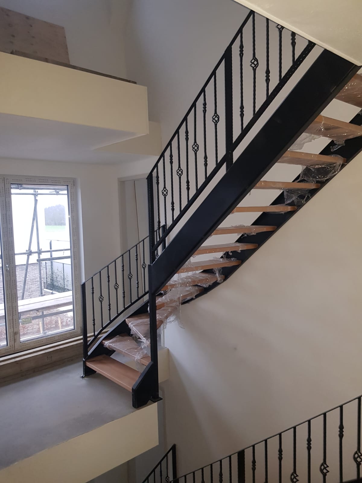 Nieuw geplaatste trap met beukenhouten treden en zwarte stalen trapboom en balustrade in een woning in aanbouw