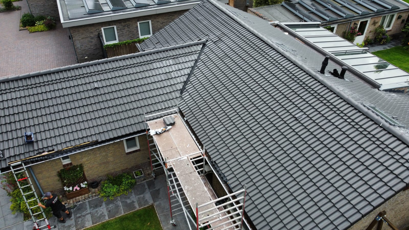 Pannendak met nieuw gelegde antraciete dakpannen tijdens werkzaamheden van de dakdekker