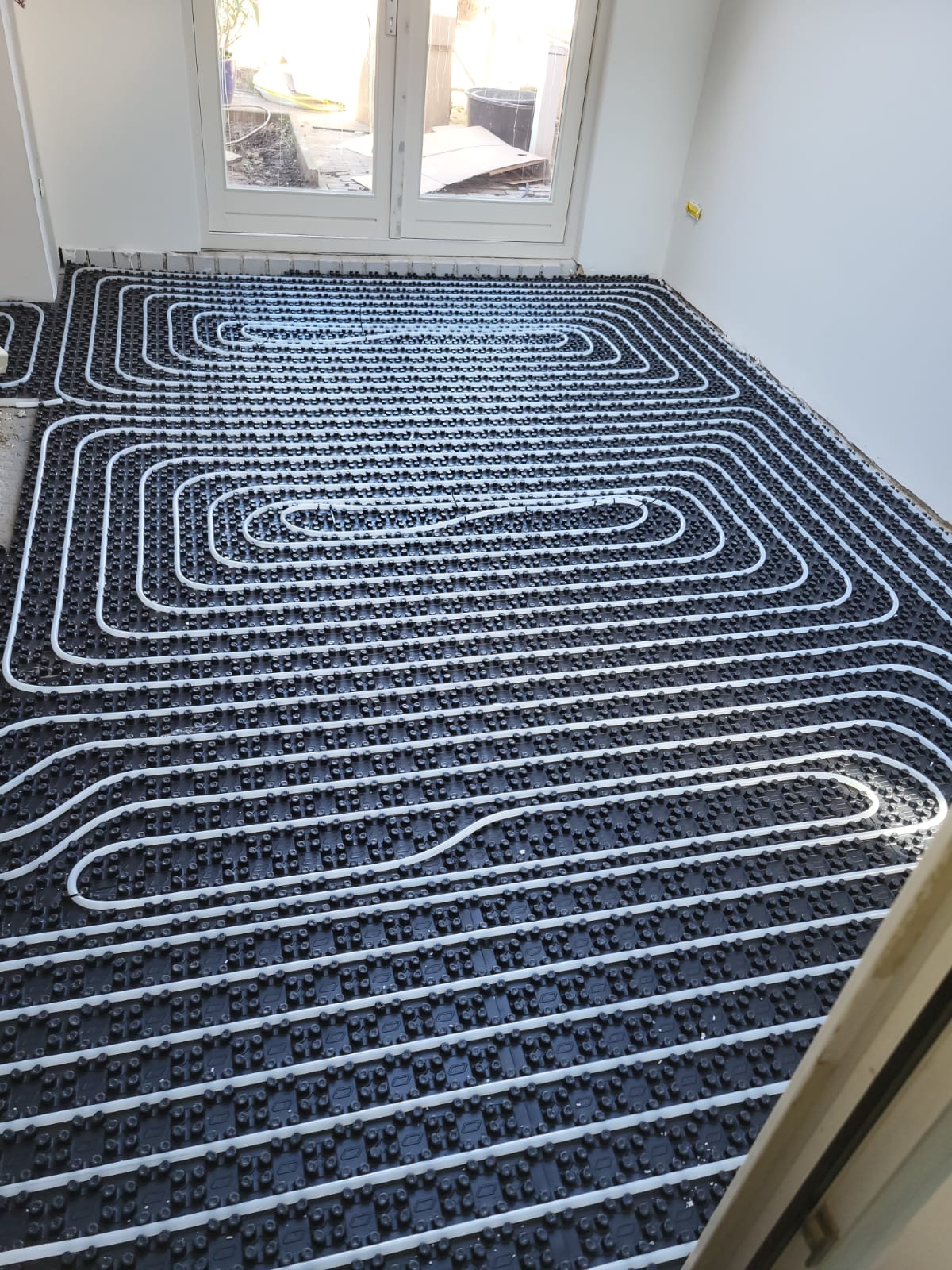 Vloerverwarming aangelegd op noppenplaten in een woning tijdens een renovatie, klaar voor de afwerkvloer