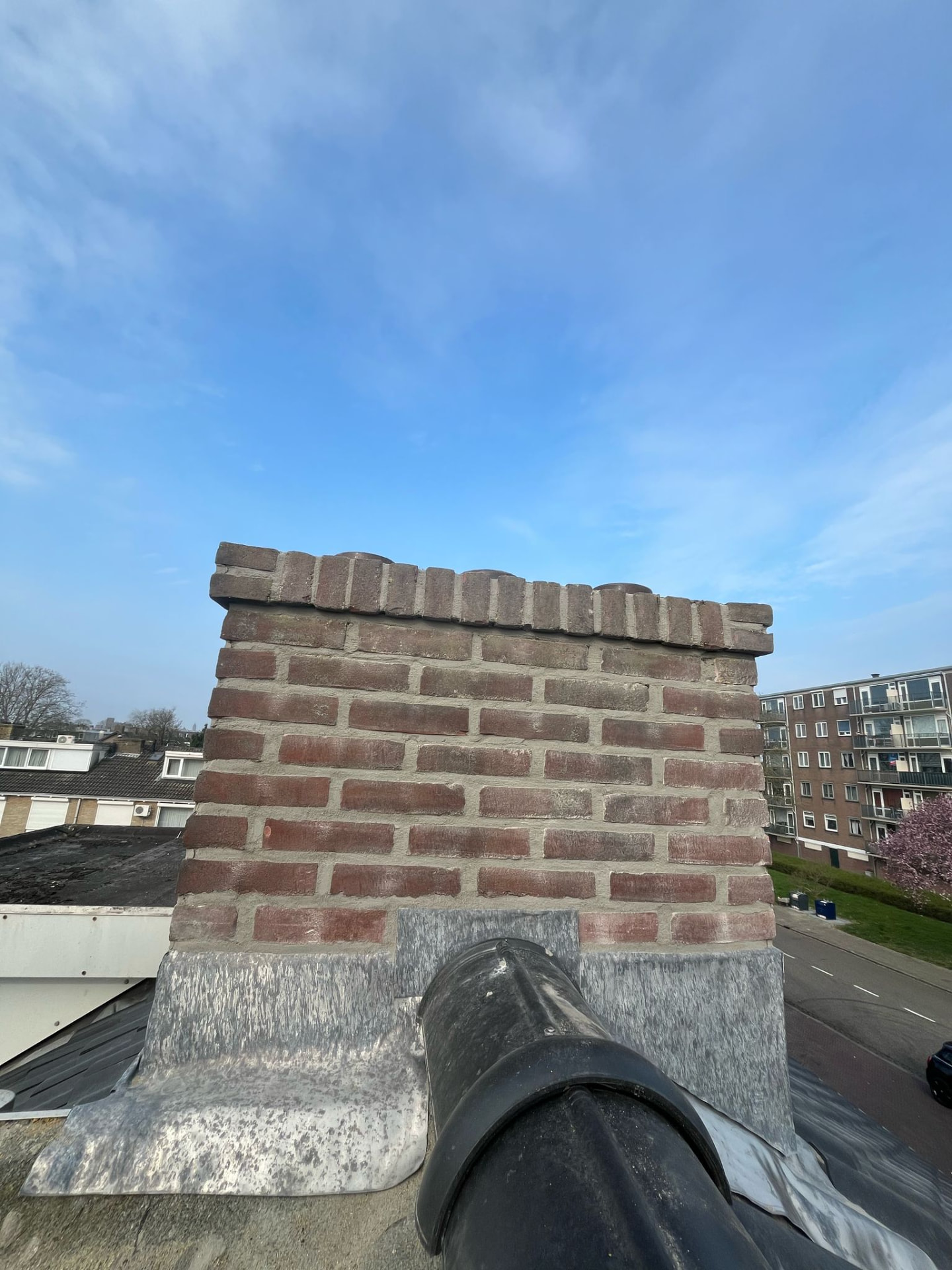 Volledig gerenoveerde gemetselde schoorsteen met nieuw voegwerk en nieuw loodwerk op een dak in Den Bosch