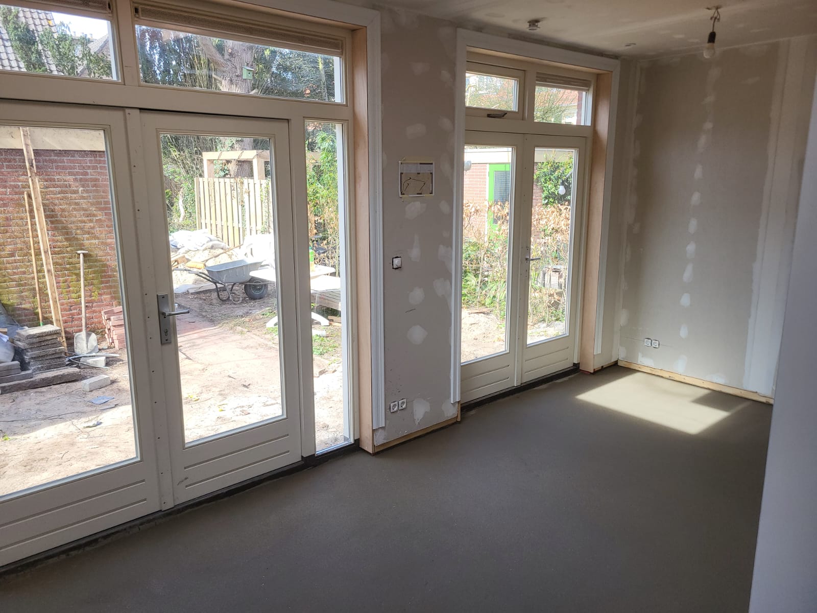 Binnenzijde van een uitbouw met nieuwe tuindeuren, bovenlichten en afgewerkte vloer